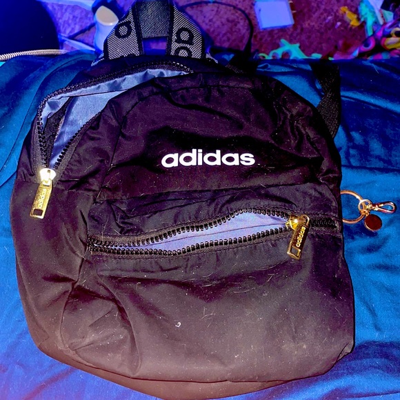 Black adidas mini backpack with white letters and gold zipper